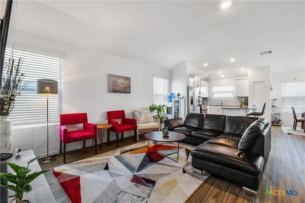 a living room with furniture kitchen view and a window