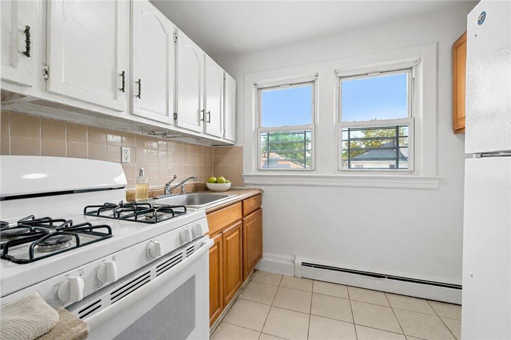 883 Manor Road Staten Island, NY 10314 - Photo 13 of 24 a kitchen with stainless steel appliances a stove a white cabinets and a window