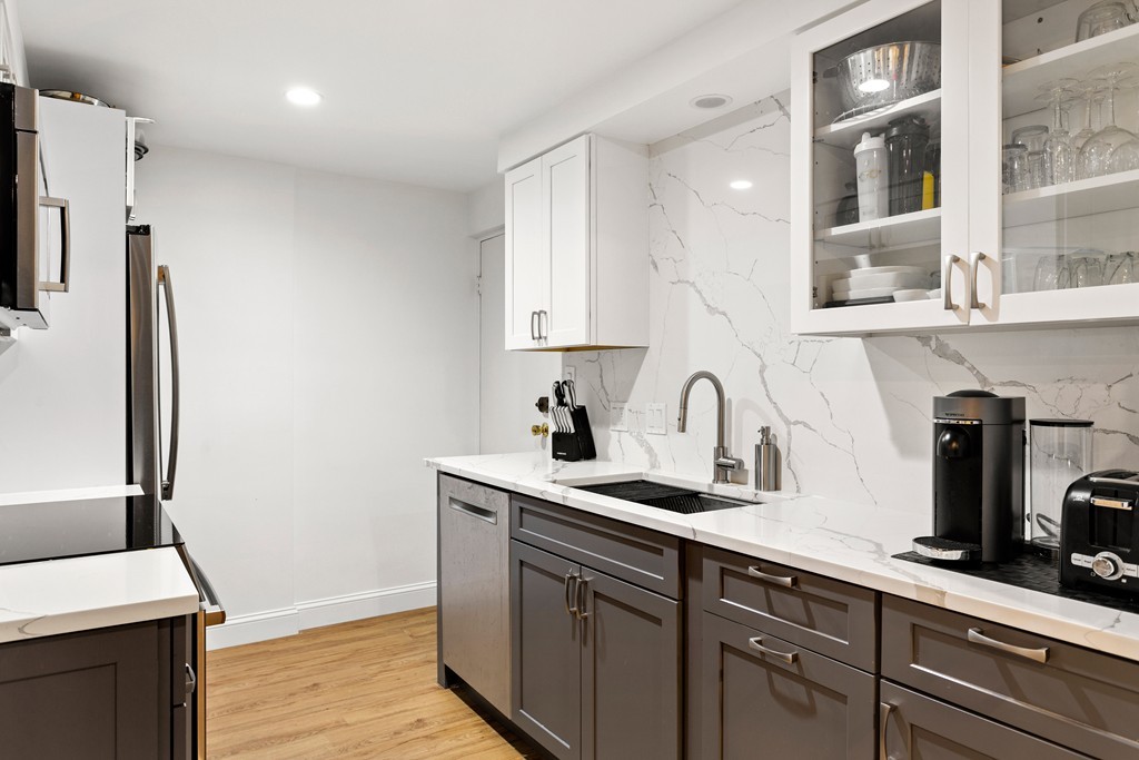 412 Langley Road, Unit 3 Newton, MA 02459 - Photo 3 of 30 a kitchen with stainless steel appliances granite countertop a sink and a stove top oven with wooden floor