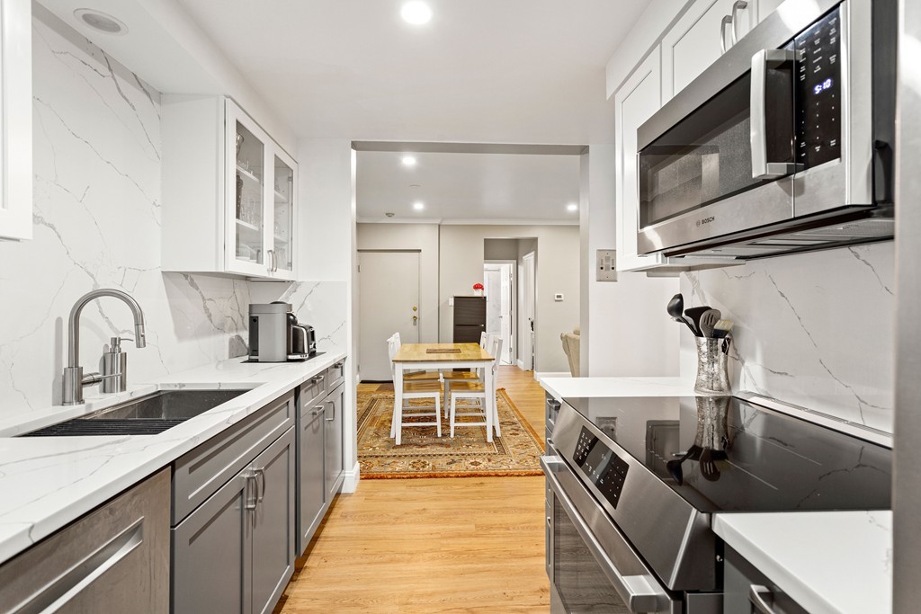 412 Langley Road, Unit 3 Newton, MA 02459 - Photo 6 of 30 a kitchen with kitchen island a sink appliances and cabinets