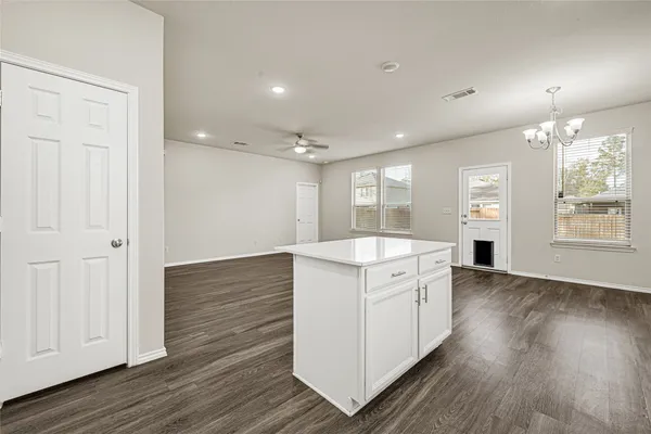an empty room with wooden floor cabinet and windows