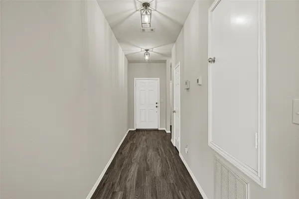 a view of a hallway with wooden floor and a chandelier