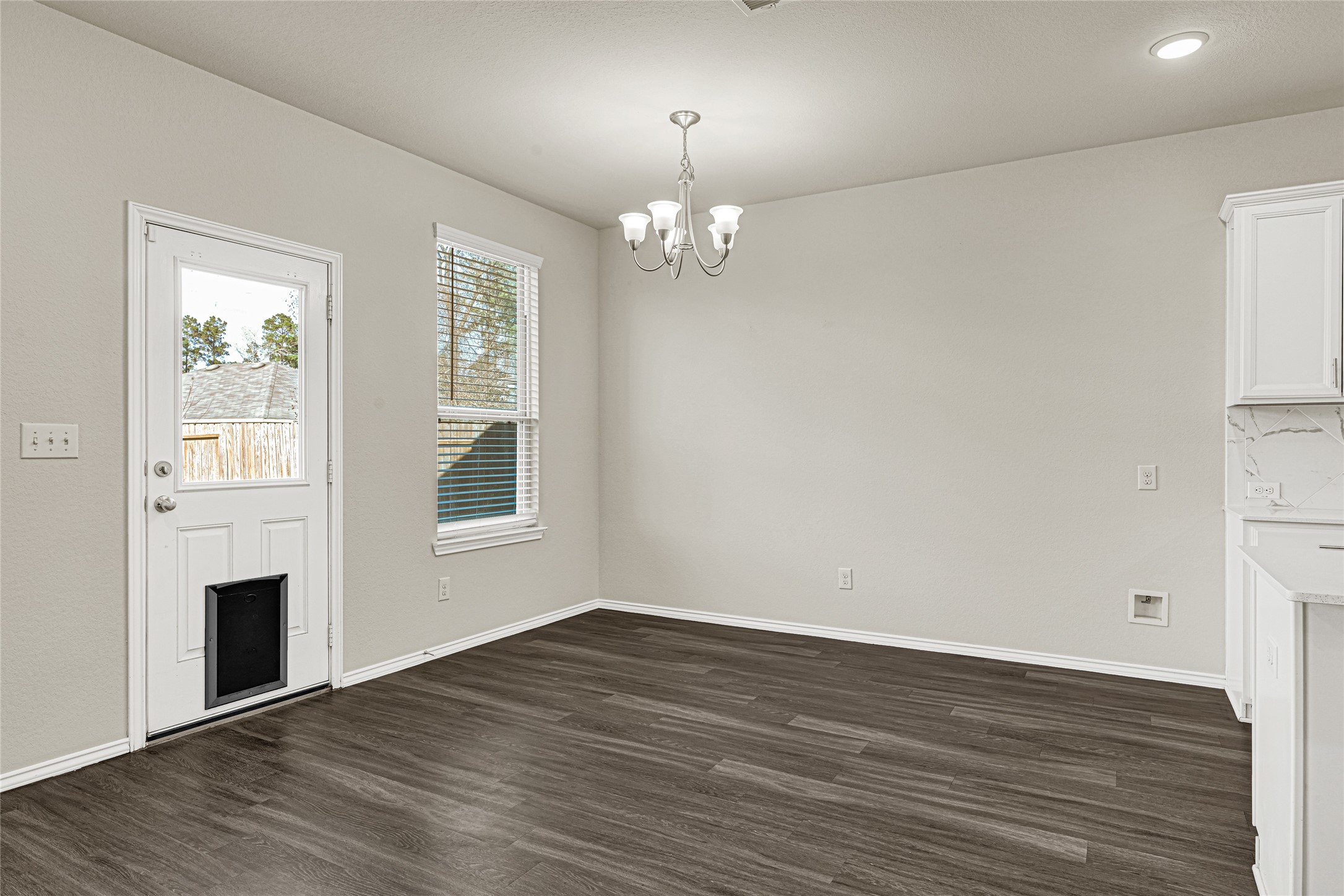 2210 Timberland Country Court Conroe, TX 77304 - Photo 10 of 25 an empty room with wooden floor chandelier and windows