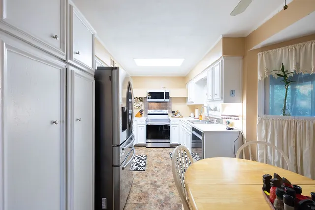 a living room with stainless steel appliances furniture a fireplace and a kitchen view