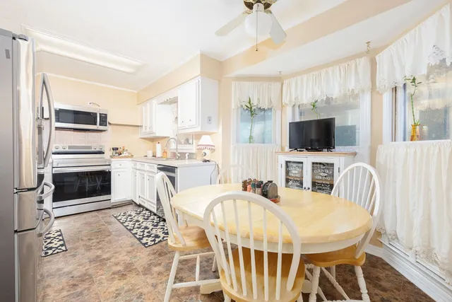 a kitchen with stainless steel appliances granite countertop a stove a sink a microwave a dining table and chairs with wooden floor