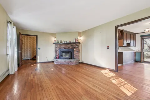an empty room with wooden floor and fireplace