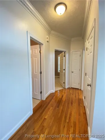 a view of a hallway with wooden floor and a bathroom