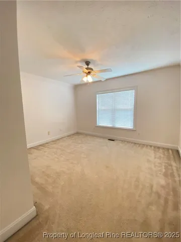 an empty room with a ceiling fan and window