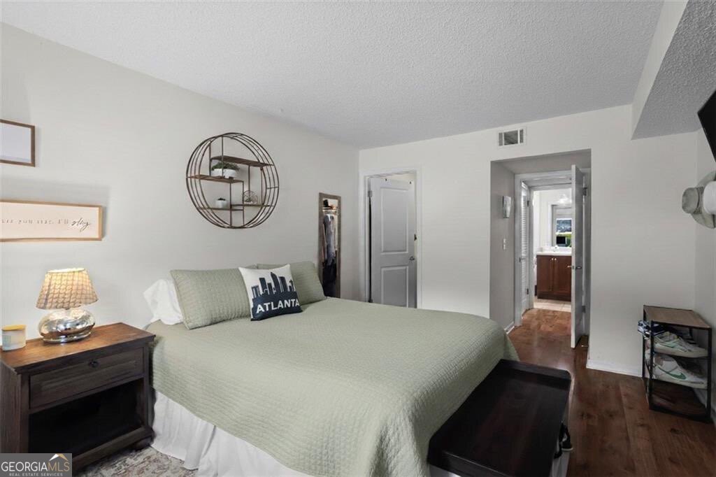 3650 Ashford Dunwoody Road Northeast, Unit 515 Atlanta, GA 30319 - Photo 9 of 14 a bedroom with a bed and wooden floor