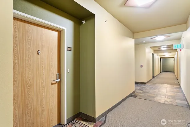 a view of a hallway with wooden floor and a bathroom