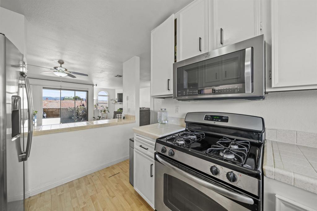 10775 Tamar Terrace, Unit A Santee, CA 92071 - Photo 34 of 38 a kitchen with stainless steel appliances a stove a microwave and cabinets