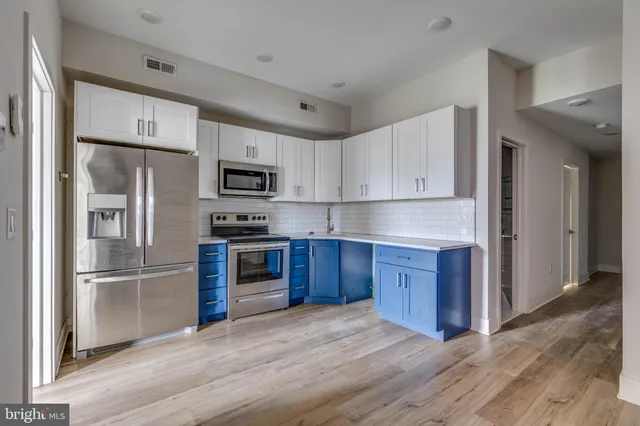 a kitchen with granite countertop wooden floors stainless steel appliances and a window