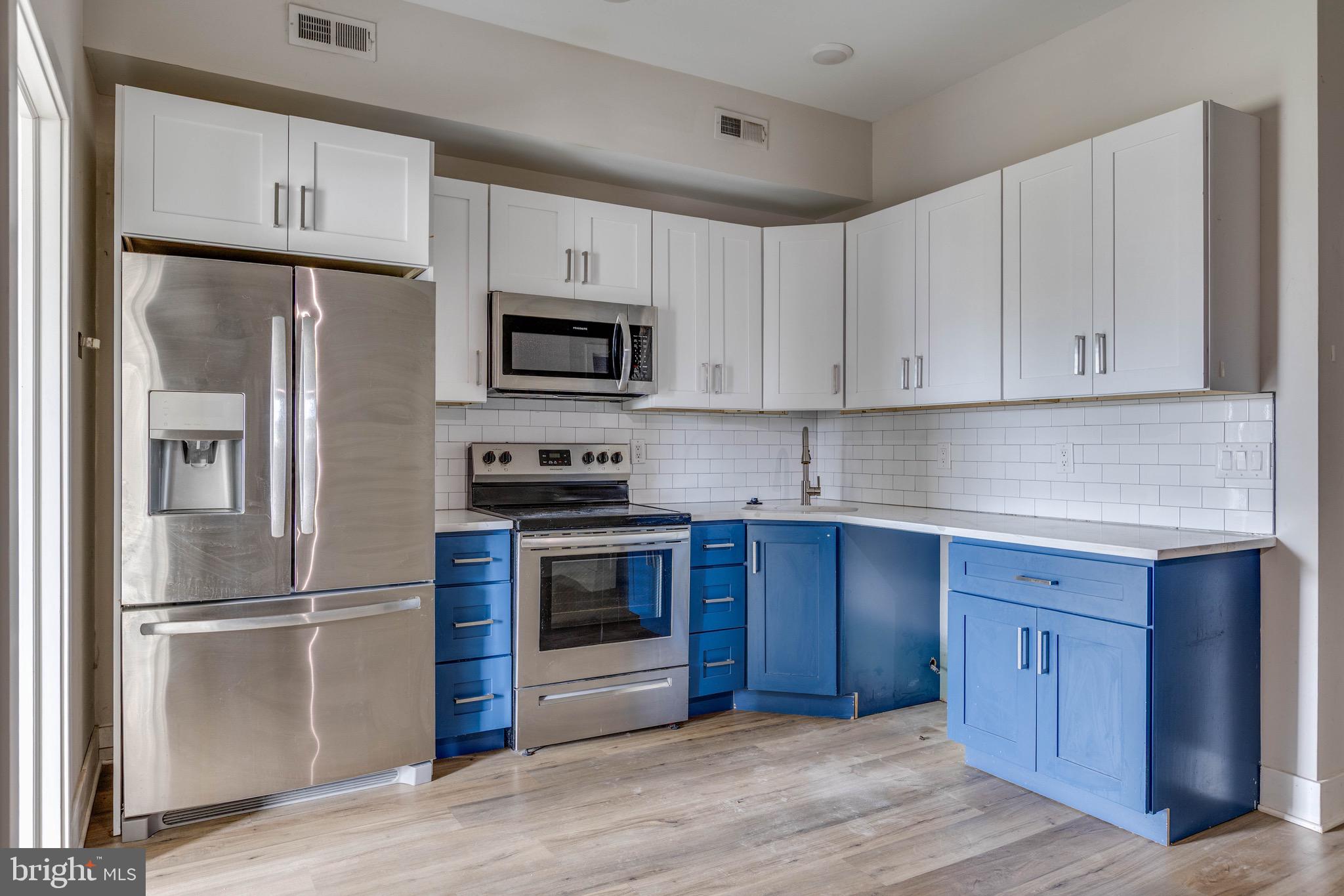 1535 North 6th Street, Unit E Philadelphia, PA 19122 - Photo 2 of 11 a kitchen with stainless steel appliances granite countertop a refrigerator stove a sink and a microwave