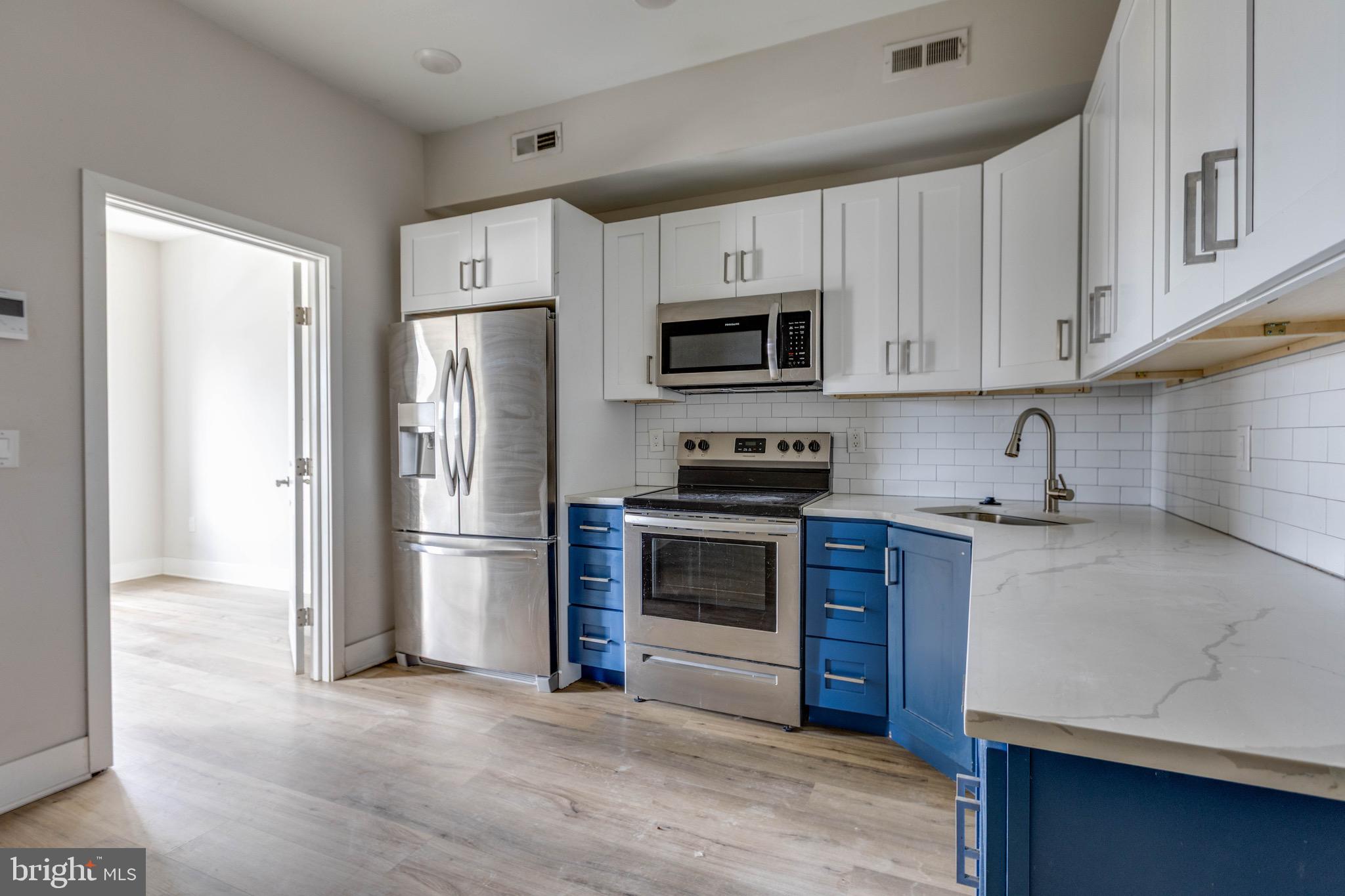 1535 North 6th Street, Unit E Philadelphia, PA 19122 - Photo 3 of 11 a kitchen with stainless steel appliances granite countertop a refrigerator stove a sink and dishwasher with wooden floor