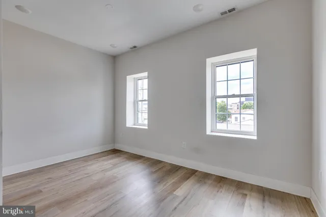 an empty room with wooden floor and windows