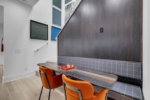 a kitchen with stainless steel appliances kitchen island granite countertop a refrigerator a stove a sink a dining table and chairs with wooden floor
