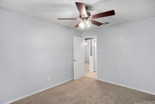 an empty room with a window and a fan