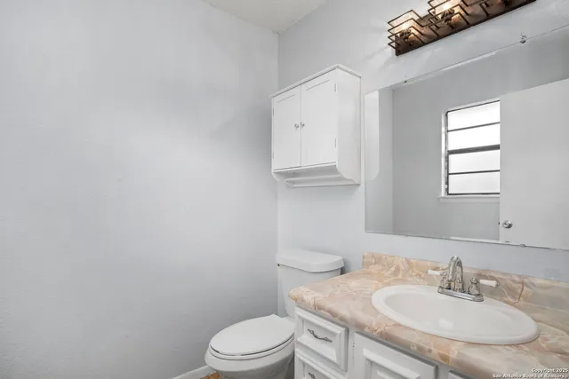 a bathroom with a granite countertop sink a toilet and mirror