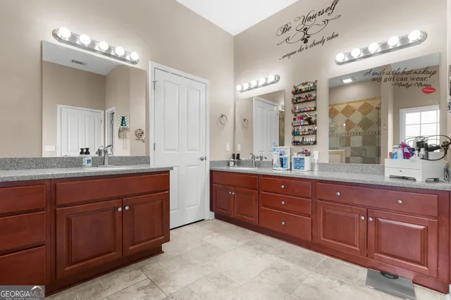a spacious bathroom with a granite countertop double vanity and a mirror