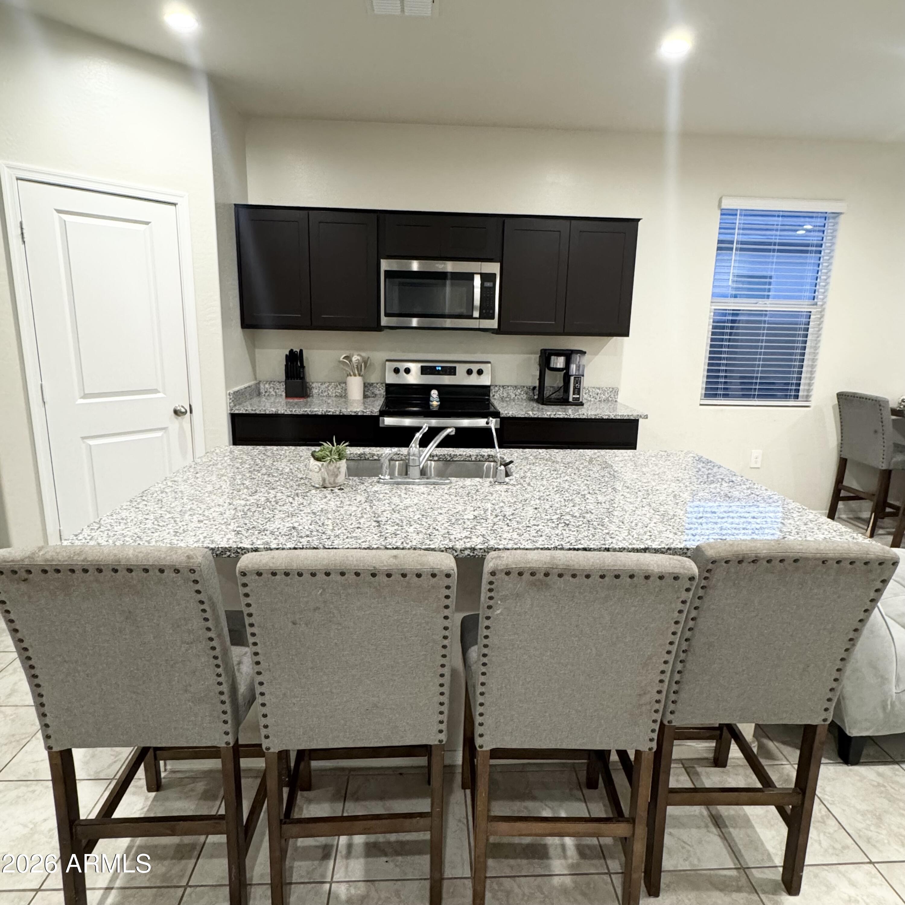 5208 East Emery Road San Tan Valley, AZ 85143 - Photo 4 of 30 a kitchen with granite countertop a table chairs microwave and sink