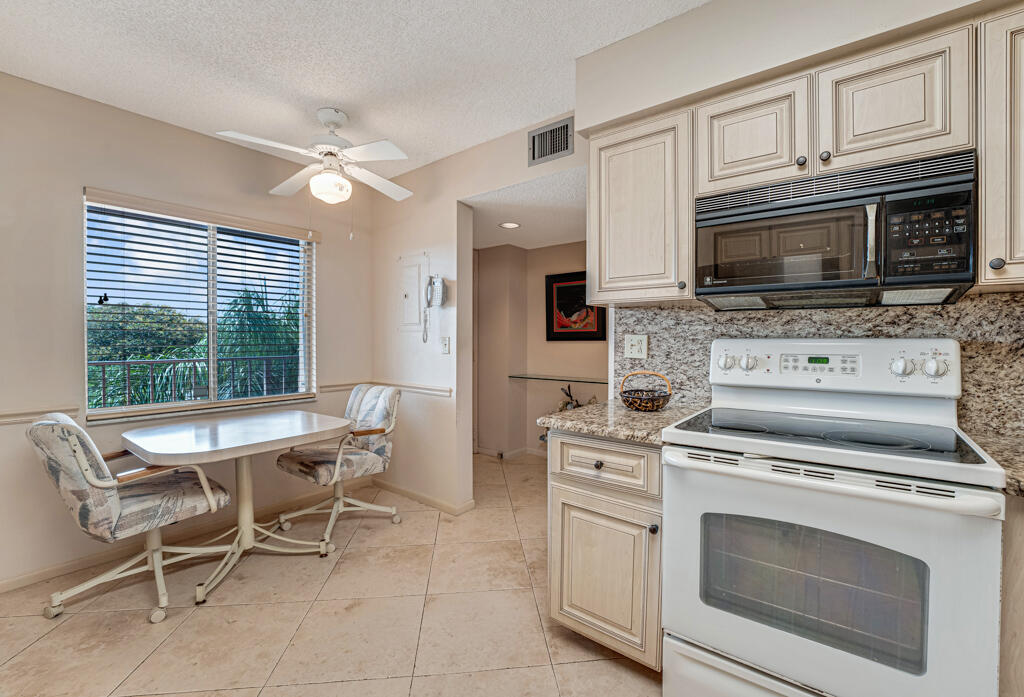 7301 Amberly Lane, Unit 407 Delray Beach, FL 33446 - Photo 11 of 23 a kitchen with a stove a microwave and furniture