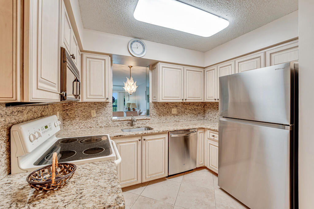 7301 Amberly Lane, Unit 407 Delray Beach, FL 33446 - Photo 8 of 23 a kitchen with a sink a refrigerator and cabinets