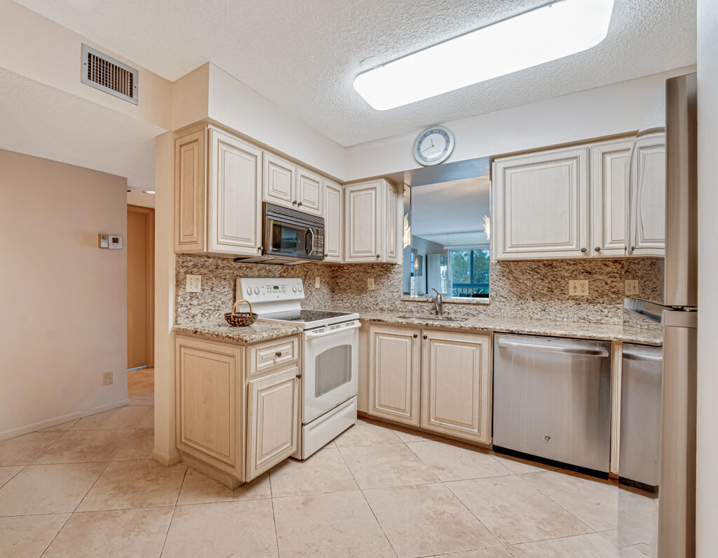 7301 Amberly Lane, Unit 407 Delray Beach, FL 33446 - Photo 9 of 23 a kitchen with stainless steel appliances granite countertop a stove top oven a sink and dishwasher