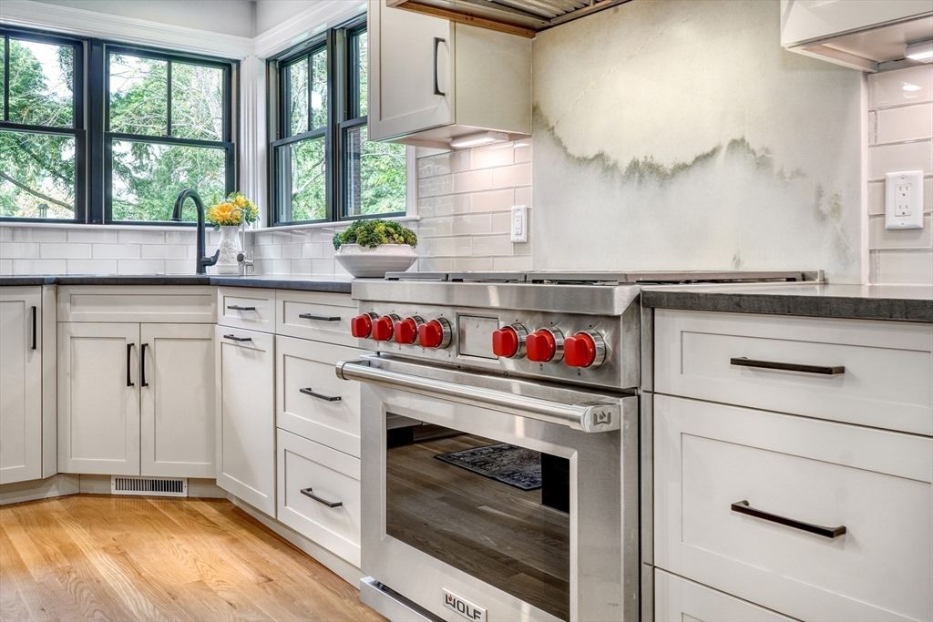 27 Cabot Street Winchester, MA 01890 - Photo 8 of 42 a kitchen with a stove and white cabinets with wooden floor