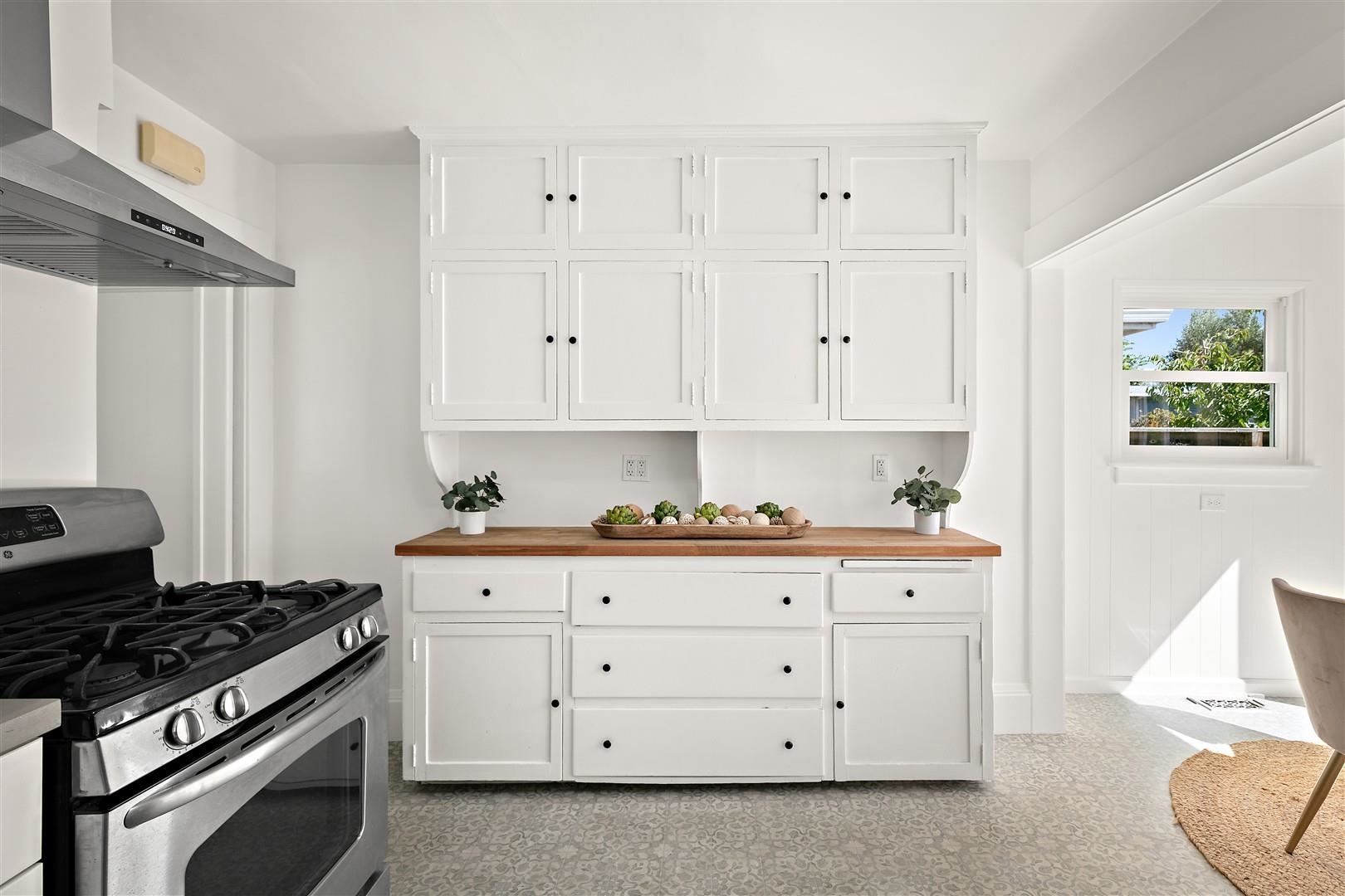 1436 Delaware Street Berkeley, CA 94702 - Photo 19 of 60 Kitchen featuring stainless steel gas stove, butcher block counters, exhaust hood, and white cabinets