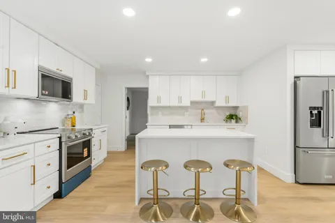 a large white kitchen with stainless steel appliances granite countertop a stove and a sink