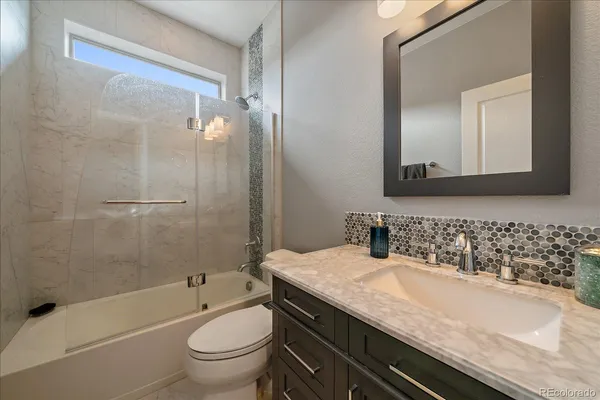 a bathroom with a granite countertop sink a toilet and shower