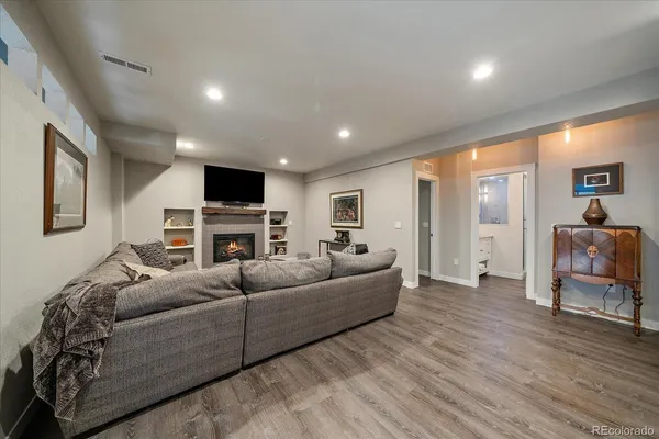 a living room with furniture a fireplace a flat screen tv and kitchen view