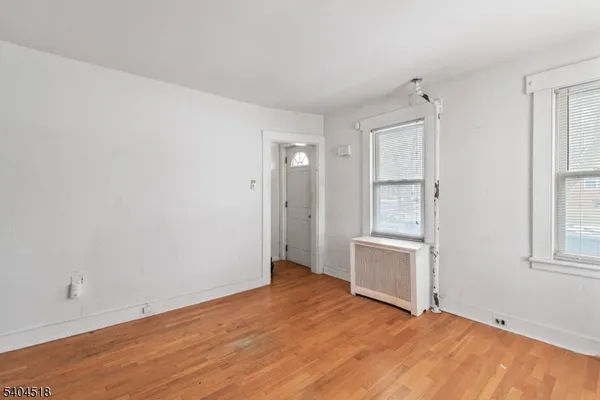 a view of an empty room with window and wooden floor