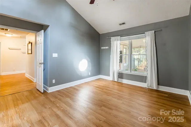 a view of an empty room with window and wooden floor