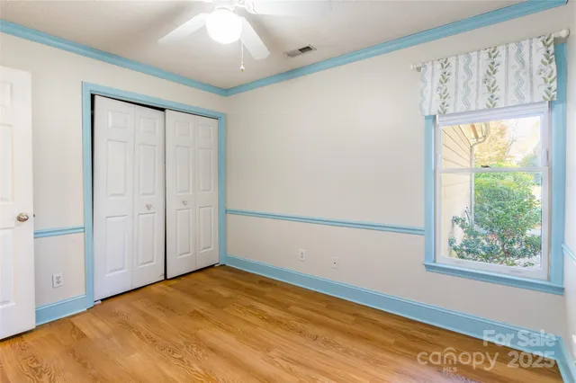 a view of empty room with wooden floor and fan