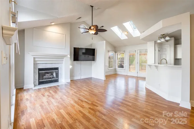a view of a livingroom with a fireplace a ceiling fan and wooden floor