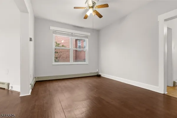 an empty room with wooden floor chandelier fan and windows