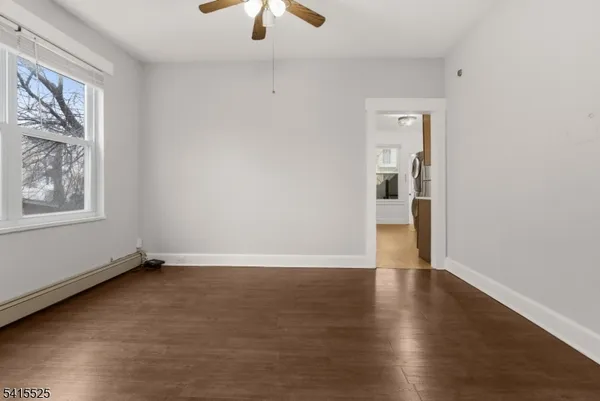 an empty room with wooden floor chandelier and windows