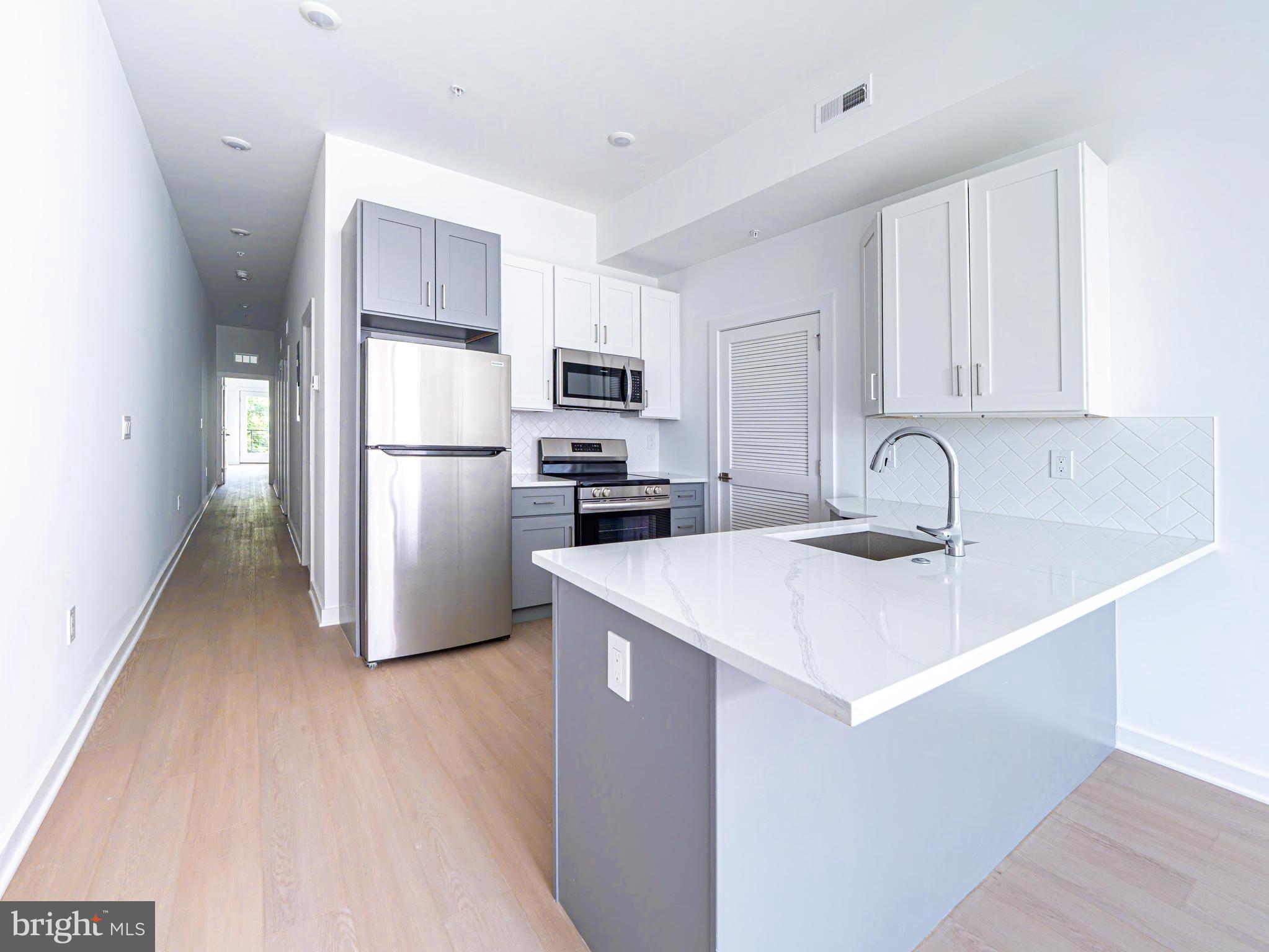 2403-2407 West Thompson Street, Unit 3 Philadelphia, PA 19121 - Photo 4 of 13 a kitchen with a sink a refrigerator a microwave and cabinets