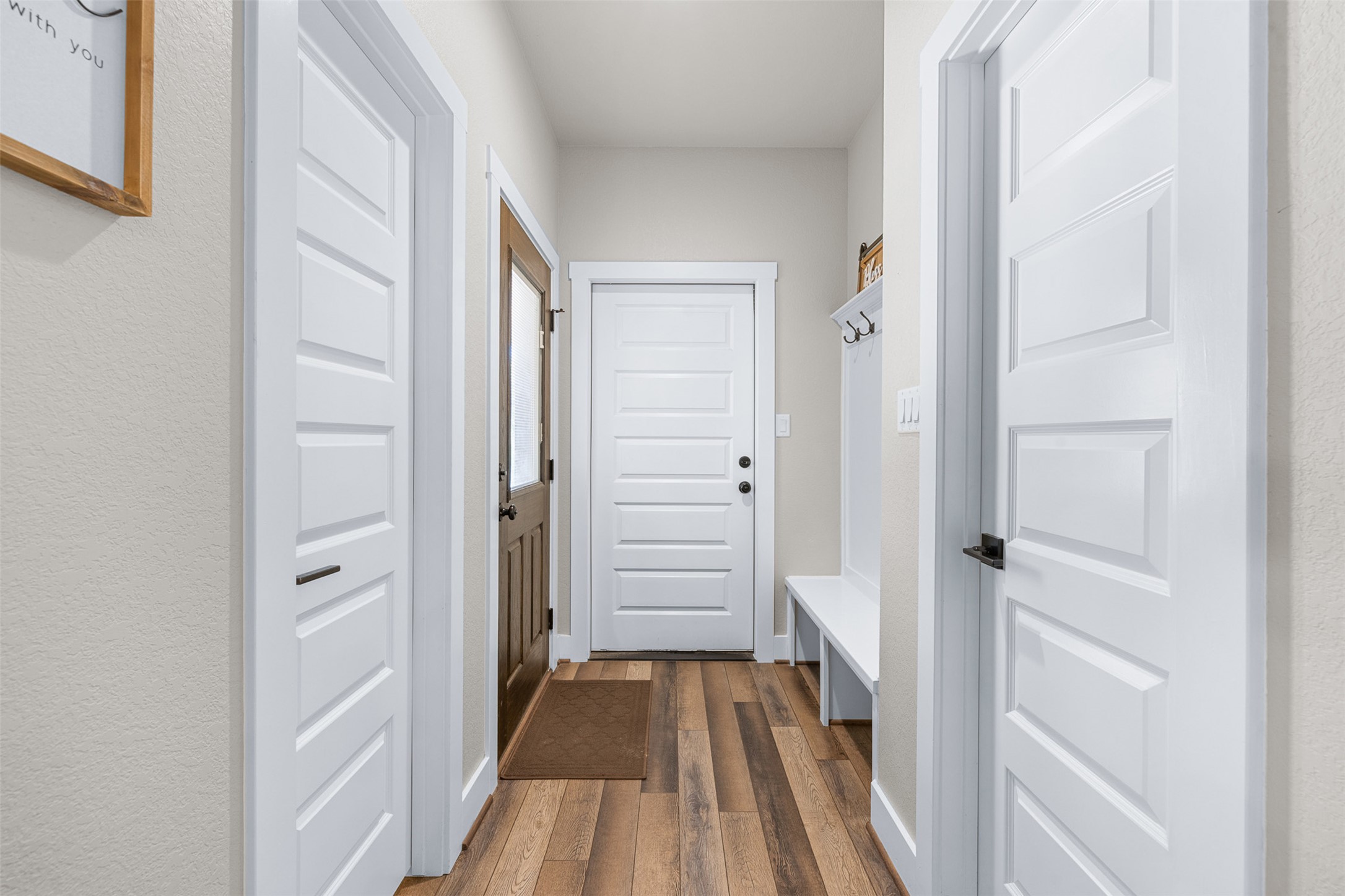1306 22 Hills Road Gause, TX 77857 - Photo 25 of 40 Inviting hallway entry featuring wood-finish flooring, white paneled doors, and a built-in bench with coat hooks