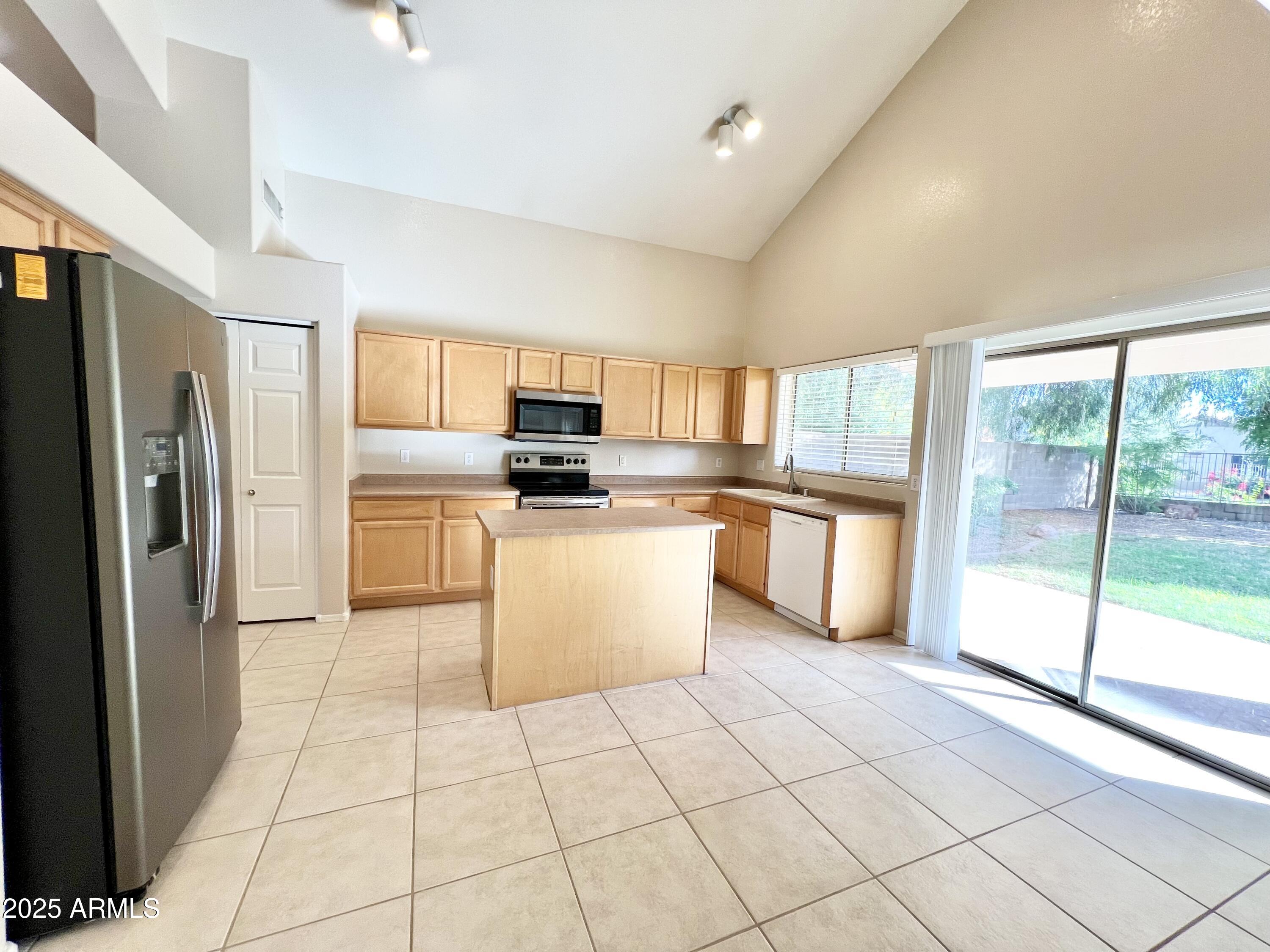 7309 West Mohawk Lane Glendale, AZ 85308 - Photo 11 of 24 a kitchen with a refrigerator a stove top oven and white cabinets