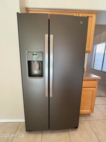 a view of a refrigerator in kitchen and an empty room
