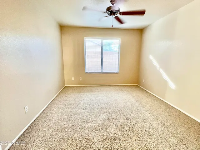 an empty room with a window and a ceiling fan