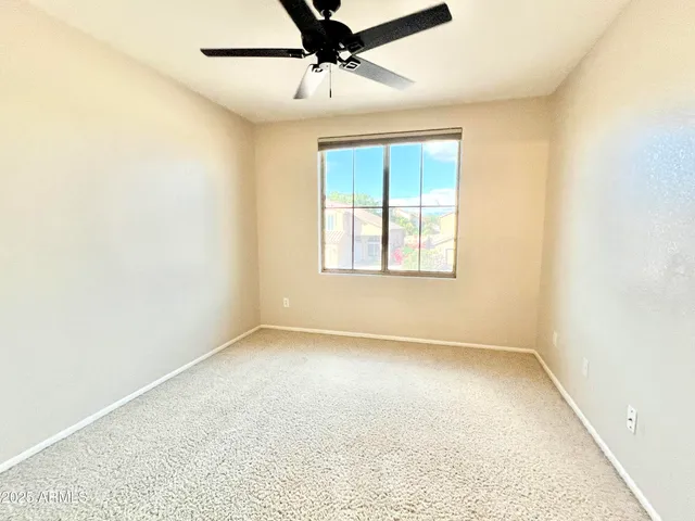 an empty room with a window and a ceiling fan