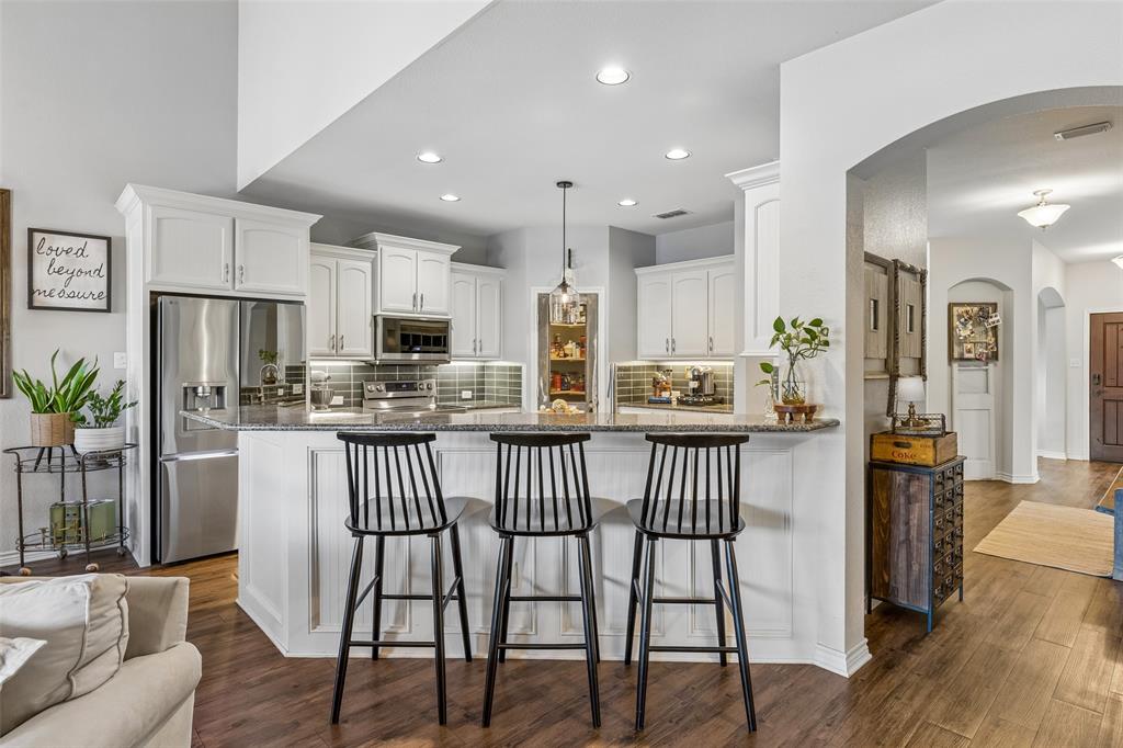 10176 Country View Lane Forney, TX 75126 - Photo 24 of 40 a kitchen with stainless steel appliances granite countertop a dining table chairs refrigerator sink and cabinets