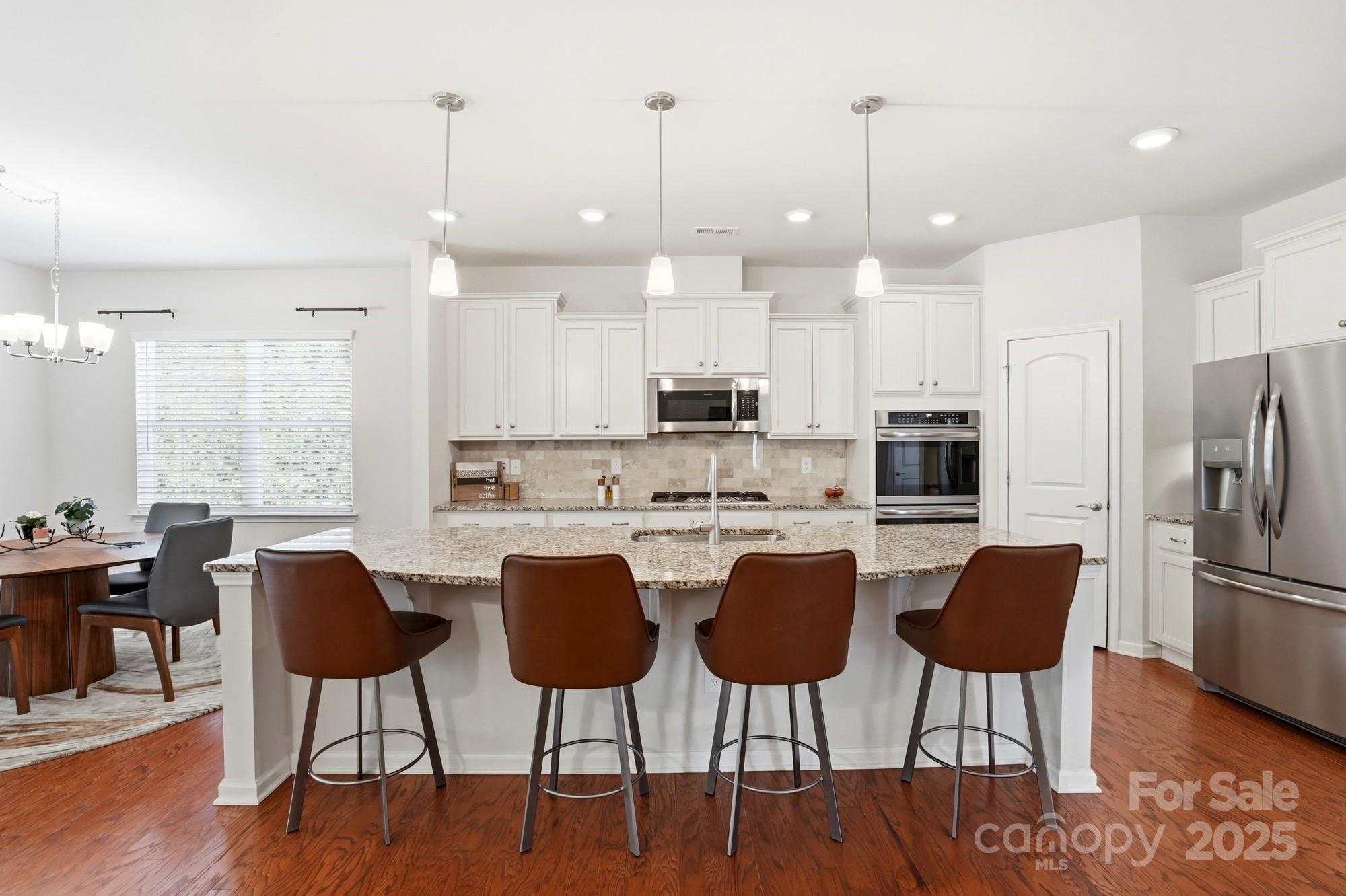 128 Van Gogh Trail Mount Holly, NC 28120 - Photo 14 of 48 a kitchen with stainless steel appliances kitchen island granite countertop a dining table chairs refrigerator and sink