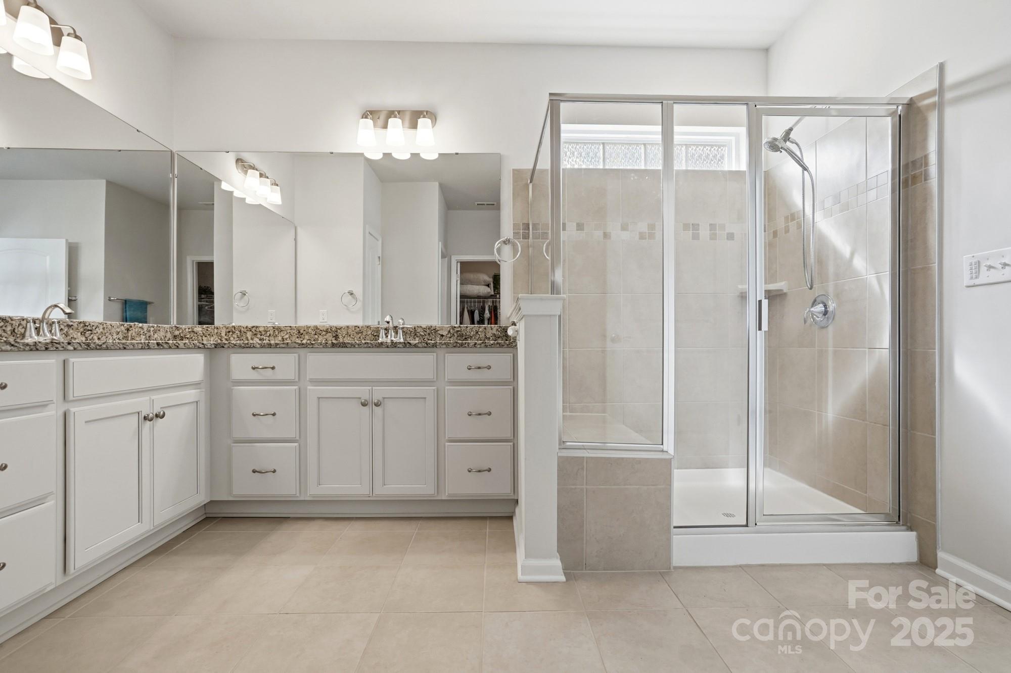 128 Van Gogh Trail Mount Holly, NC 28120 - Photo 28 of 48 a spacious bathroom with a granite countertop sink a mirror a vanity and a shower