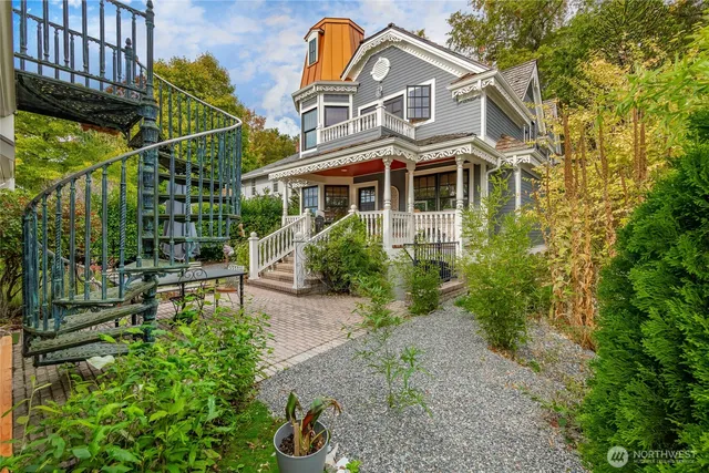 a view of a brick house with plants and large trees
