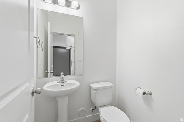 1173 West 1870 South Logan, UT 84321 - Photo 7 of 33 White pedestal sink with a chrome faucet, illuminated by a three-light vanity fixture