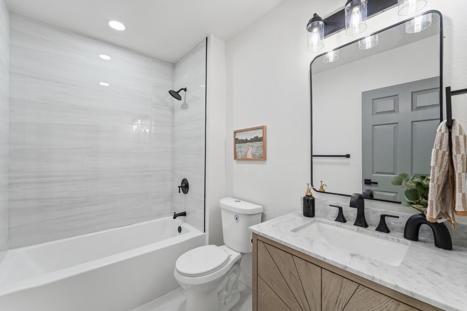 430 Laurel Avenue Modesto, CA 95351 - Photo 6 of 28 a bathroom with a sink a toilet a mirror a bathtub and shower